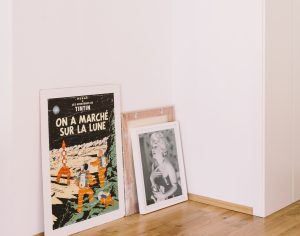 Several paintings and posters leaning against the wall to be used in an interior design project