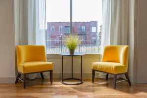 Simplistic home design of two yellow chairs facing a small table with plant