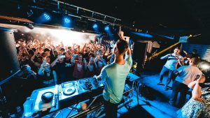 View from behind the stage looking over the DJ into the crowd of a busy night club