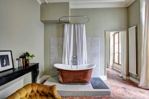 Opulent home with bathtub upon marble platform in centre of bedroom