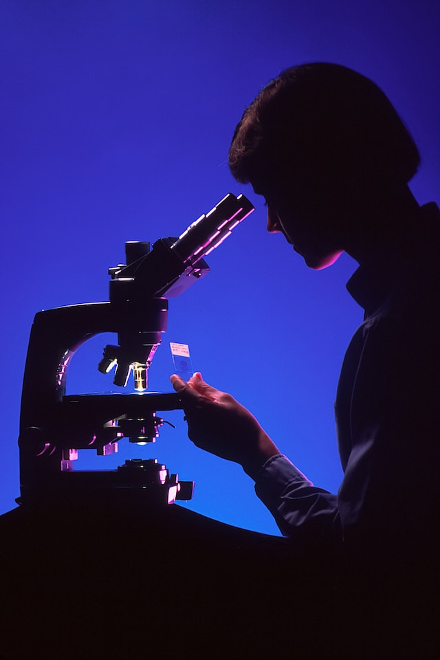 silhouette of a person looking at a microscope